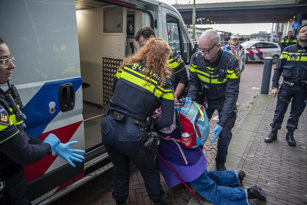 Politieagenten die een rebel in een arrestatiebus slepen.