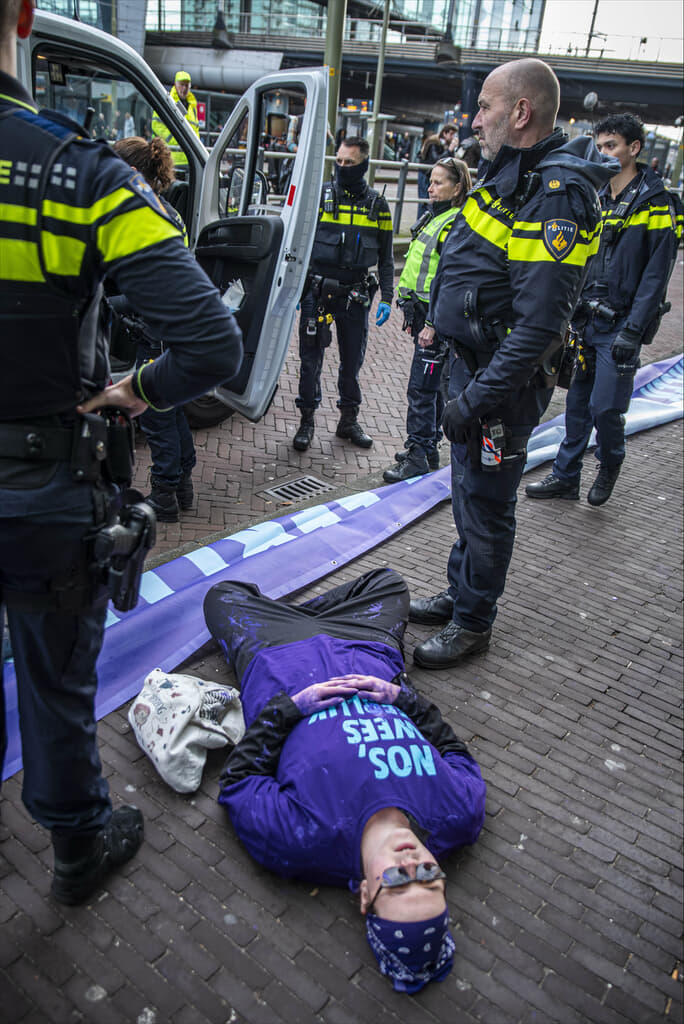 Rebel liggend op de grond met politieagenten er omheen.