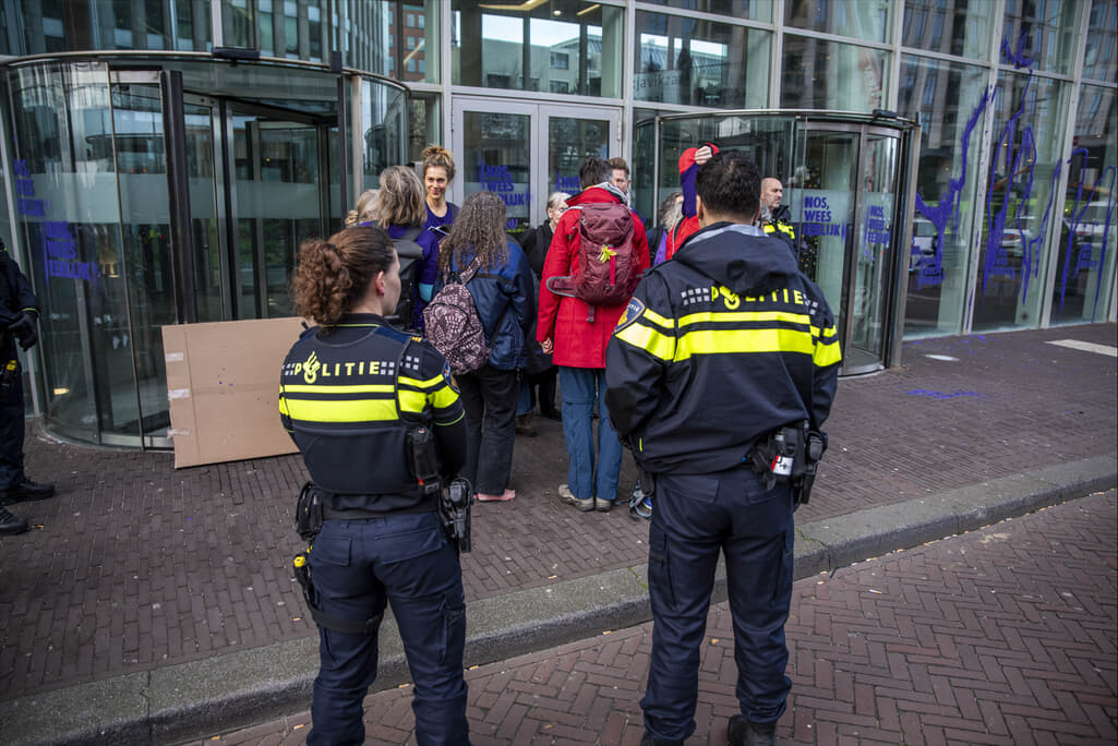 Groep rebellen met politieagenten op de voorgrond.