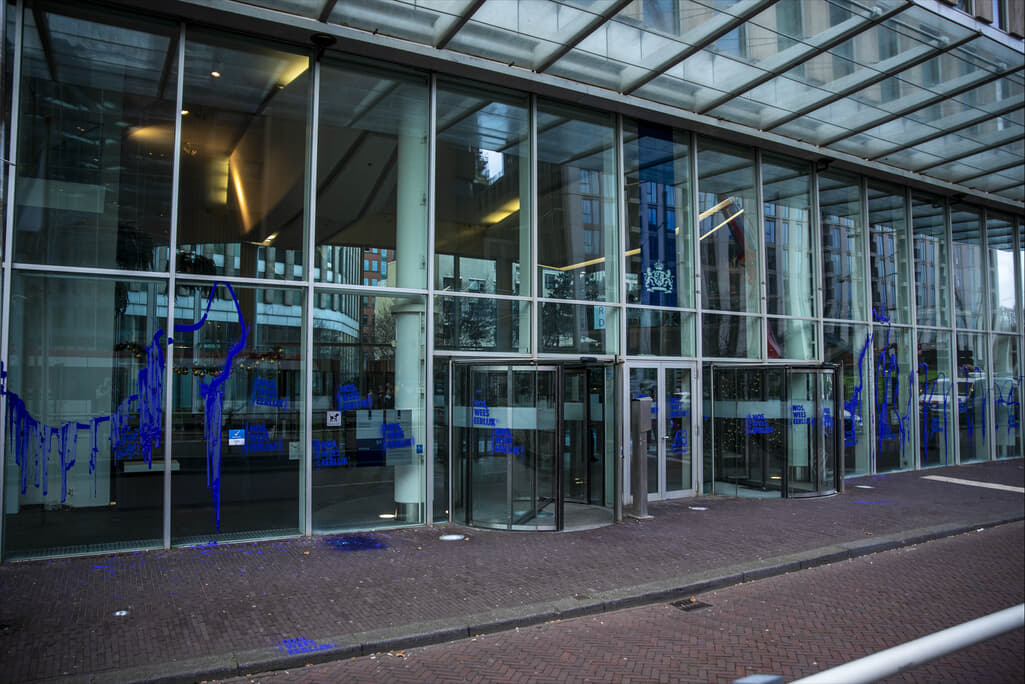 Voorgevel beklad met paarse verf en “NOS, Wees Eerlijk!” in krijtverf.