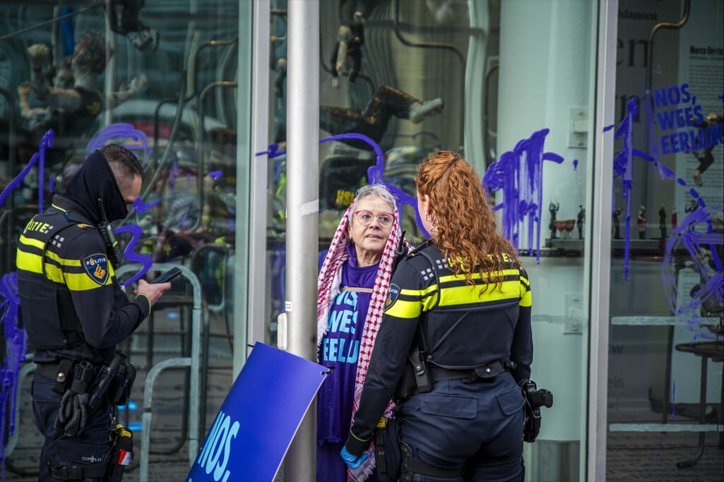 Rebel met een keffiyeh over het hoofd in gesprek met twee politieagenten.